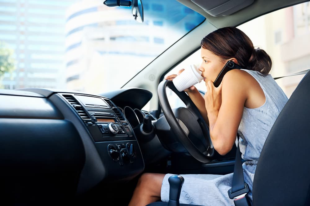 woman drinking coffee distracted while driving