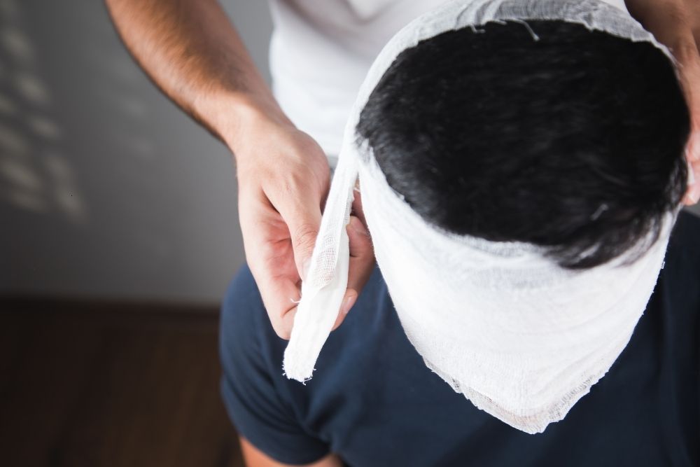 Nurse places a bandage on a patient's forehead