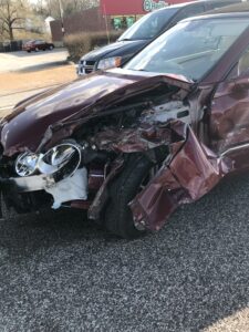 extensive front end damage to red sedan after car crash