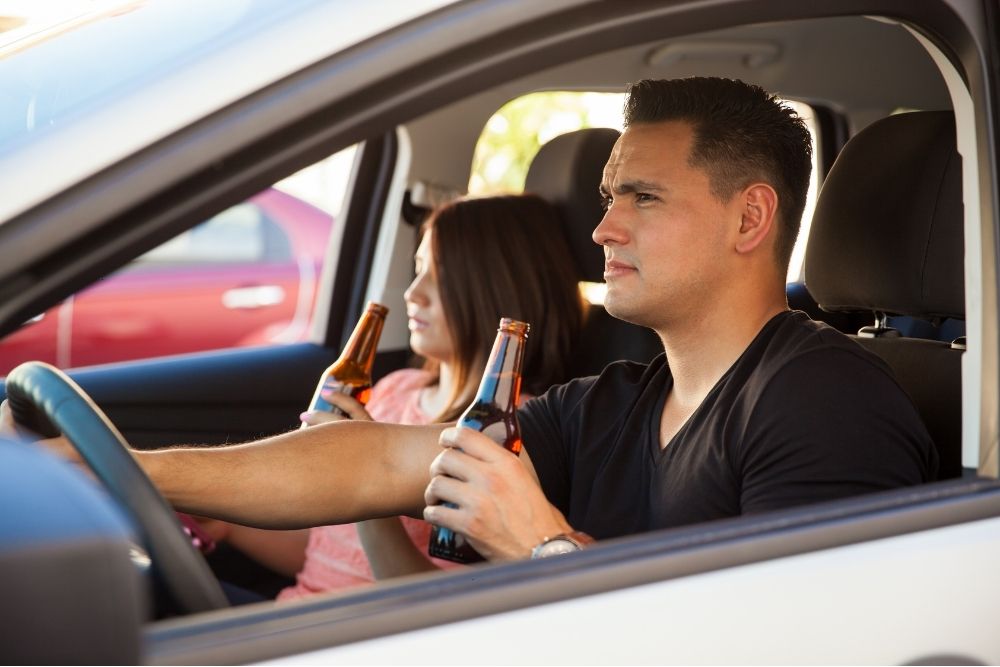 Car driver drinking while driving