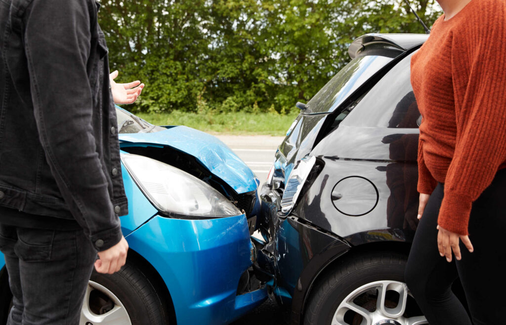 Two drivers inspect vehicle damage after a crash requiring St Louis uninsured motorist lawyers.